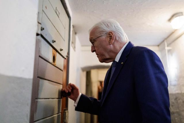 German President Frank-Walter Steinmeier peers into a detention cell as he visits the memorial site of the former Closed Youth Detention Centre (Geschlossener Jugendwerkhof Torgau - GJWH) in Torgau, eastern Germany on April 22, 2026. According to the memorial site, the closed youth detention centre used to be the only closed residential care facility in the GDR, where young people were to be re-educated into "socialist personalities" within just a few months. During the course of GDR history, approximately 135,000 children and young people were forced to go through socialist re-education practices in youth work camps and special children's homes. Historical traces at the memorial site are visible in the former solitary confinement cells and courtyard. (Photo by Jens SCHLÜTER / POOL / AFP)
