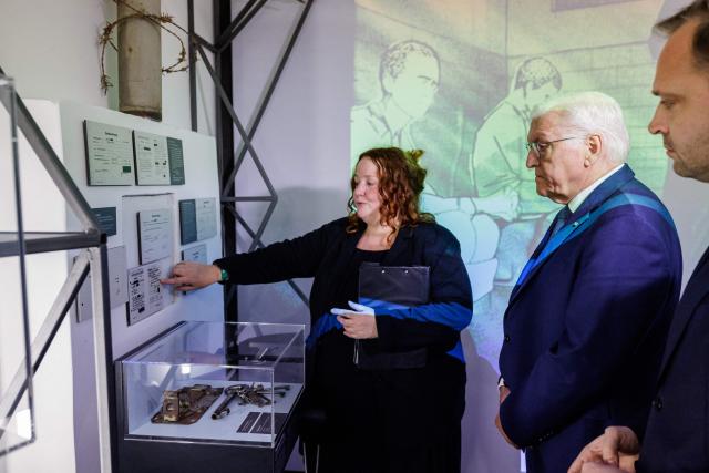 German President Frank-Walter Steinmeier (C) and President of Saxony's State Parliament Alexander Dierks (R) listen as Manuela Rummel, Director of Educational Programs at the Memorial, gives explanations during a tour of the exhibition at the memorial site of the former Closed Youth Detention Centre (Geschlossener Jugendwerkhof Torgau - GJWH) in Torgau, eastern Germany on April 22, 2026. According to the memorial site, the closed youth detention centre used to be the only closed residential care facility in the GDR, where young people were to be re-educated into "socialist personalities" within just a few months. During the course of GDR history, approximately 135,000 children and young people were forced to go through socialist re-education practices in youth work camps and special children's homes. Historical traces at the memorial site are visible in the former solitary confinement cells and courtyard. (Photo by Jens SCHLÜTER / POOL / AFP)