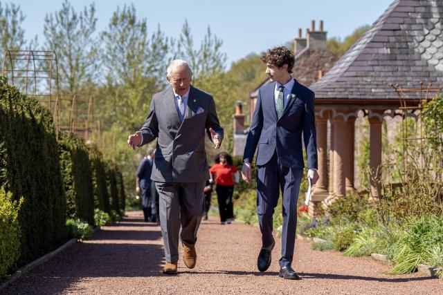 Joel Mawhinney (R), a presenter with British children's television programme Blue Peter, listens to Britain's King Charles III (L), as they walk before presenting him with the Blue Peter Green Badge to recognise his work to protect nature and the environment, at Dumfries House near Cumnock, south of Glasgow, Scotland on April 22, 2026. (Photo by Jane Barlow / POOL / AFP)