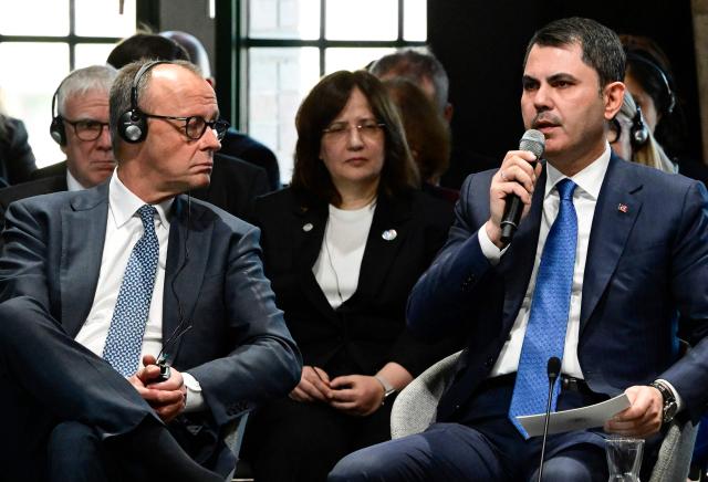 German Chancellor Friedrich Merz (L) listens to Turkey's Minister of Environment, Urbanization and Climate Change Murat Kurum during the Petersberg Climate Dialogue (PCD) conference, on April 22, 2026 at the Westhafen Convention Center (WECC) in Berlin. The Petersberg Climate Dialogue is the first major COP31-related event that will be held in Antalya, Turkey, from November 9 to 20, 2026. (Photo by John MACDOUGALL / AFP)