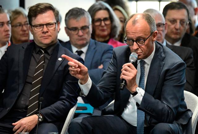 German Minister for the Environment, Climate Protection, Nature Conservation and Nuclear Safety Carsten Schneider (L) listens as Germany's Chancellor Friedrich Merz addresses guests during the Petersberg Climate Dialogue (PCD) conference, on April 22, 2026 at the Westhafen Convention Center (WECC) in Berlin. The Petersberg Climate Dialogue is the first major COP31-related event that will be held in Antalya, Turkey, from November 9 to 20, 2026. (Photo by John MACDOUGALL / AFP)
