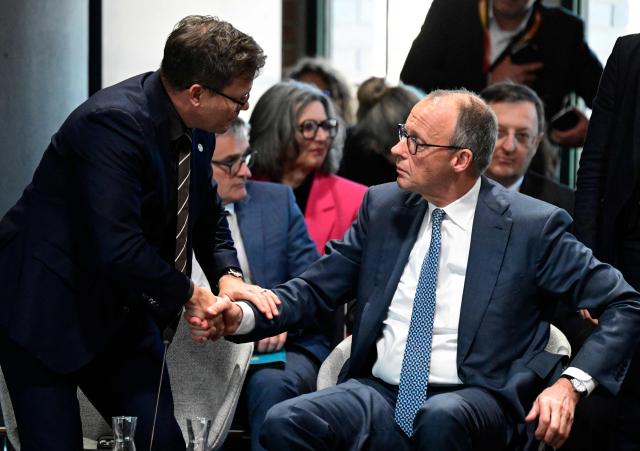 German Minister for the Environment, Climate Protection, Nature Conservation and Nuclear Safety Carsten Schneider (L) shakes hands with Germany's Chancellor Friedrich Merz as he leaves the Petersberg Climate Dialogue (PCD) conference, on April 22, 2026 at the Westhafen Convention Center (WECC) in Berlin. The Petersberg Climate Dialogue is the first major COP31-related event that will be held in Antalya, Turkey, from November 9 to 20, 2026. (Photo by John MACDOUGALL / AFP)