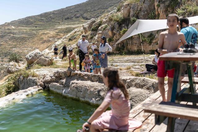 Israelis enjoy the Palestinian water spring of Ein al-Rashash as they celebrate the Israeli Independence Day at the settlement of Malachei HaShalom, northeast of Ramallah in the occupied West Bank, on April 22, 2026. (Photo by ilia YEFIMOVICH / AFP)