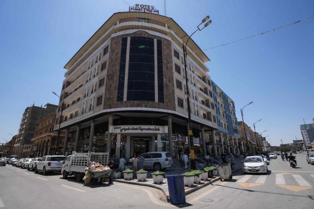 People stand outside a hotel in Najaf on April 22, 2026. The International Monetary Fund sharply reduced its 2026 growth forecast for the Middle East and North Africa to 1.1 percent on April 14, as war chokes Gulf oil and gas exports. Iran, Iraq and Qatar will be particularly hard-hit, the IMF's World Economic Outlook warned, with Iraq’s economy projected to contract by 6.8 percent. (Photo by Qassem al-KAABI / AFP)