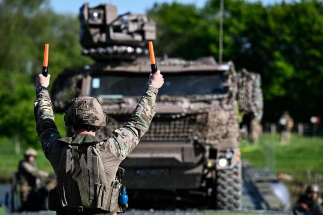 A member of France's 1st Tirailleur Regiment gestures to help an army vehicle to cross Lake Amance, during a training session as part of the ORION 26 military exercise in Radonvilliers, northeastern France, on April 22, 2026. (Photo by Jean-Christophe VERHAEGEN / AFP)