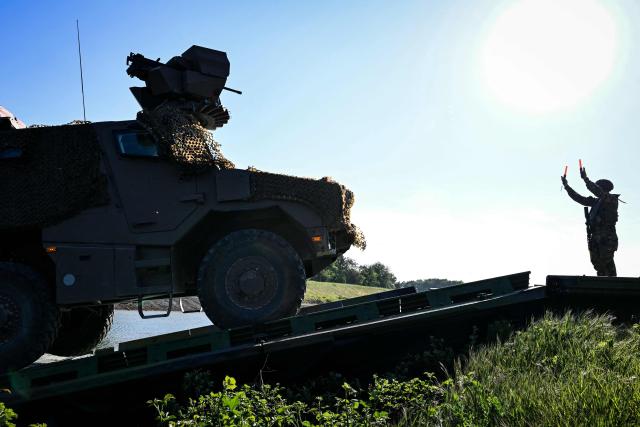 A member of France's 1st Tirailleur Regiment gestures to help an army vehicle to cross Lake Amance, during a training session as part of the ORION 26 military exercise in Radonvilliers, northeastern France, on April 22, 2026. (Photo by Jean-Christophe VERHAEGEN / AFP)