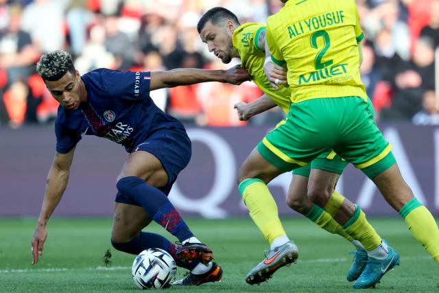 Paris Saint-Germain's French midfielder #14 Desire Doue (L) fights for the ball with Nantes' French defender #24 Frederic Guilbert (C) during the French L1 football match between Paris Saint-Germain (PSG) and FC Nantes at the Parc des Princes stadium in Paris on April 22, 2026. (Photo by FRANCK FIFE / AFP)