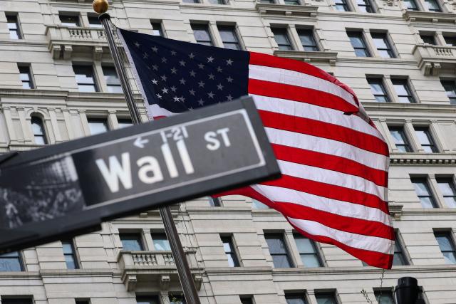 The American flag flies behind a Wall Street sign near the New York Stock Exchange (NYSE) in New York City on April 22, 2026. (Photo by ANGELA WEISS / AFP)