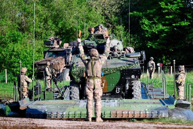 A member of France's 1st Tirailleur Regiment gestures to help an army vehicle to cross Lake Amance, during a training session as part of the ORION 26 military exercise in Radonvilliers, northeastern France, on April 22, 2026. (Photo by Jean-Christophe VERHAEGEN / AFP)