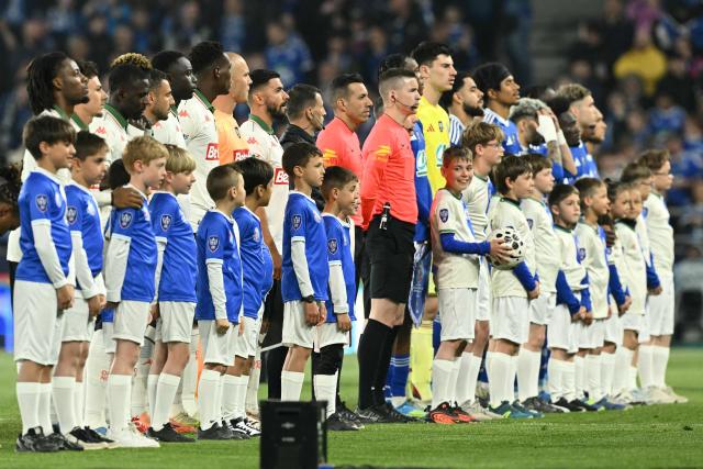 Players, match officials and mascots stand ahead of the French Cup semi-final football match between RC Strasbourg Alsace and OGC Nice at the Stade de la Meinau in Strasbourg, eastern France, on April 22, 2026. (Photo by SEBASTIEN BOZON / AFP)