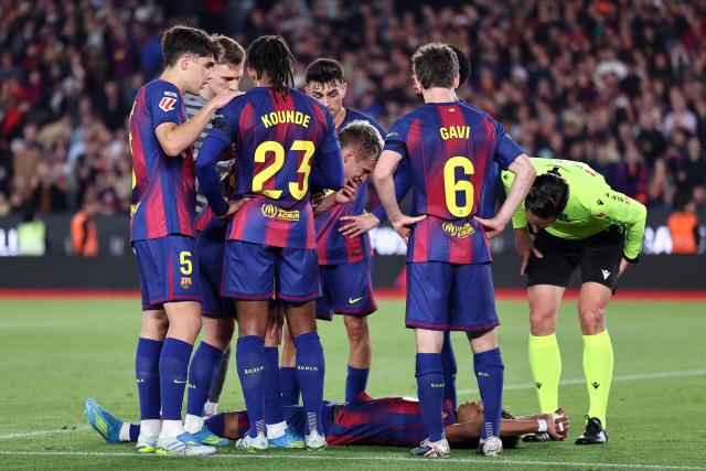 Spanish referee Jose Luis Munuera (R) and teammates check on Barcelona's Spanish forward #10 Lamine Yamal after sustaining an injury during the Spanish league football match between FC Barcelona and RC Celta de Vigo at Camp Nou stadium in Barcelona on April 22 , 2026. (Photo by Josep LAGO / AFP)