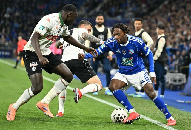 Strasbourg's British midfielder #20 Martial Godo (R) runs with the ball during the French Cup semi-final football match between RC Strasbourg Alsace and OGC Nice at the Stade de la Meinau in Strasbourg, eastern France, on April 22, 2026. (Photo by SEBASTIEN BOZON / AFP)