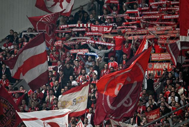 Bayern Munich fans display their scarves and wave flags during the German Cup (DFB-Pokal) semi-final football match between Bayer 04 Leverkusen and FC Bayern Munich in Leverkusen, western Germany on April 22, 2026. (Photo by INA FASSBENDER / AFP) / DFB REGULATIONS PROHIBIT ANY USE OF PHOTOGRAPHS AS IMAGE SEQUENCES AND QUASI-VIDEO.