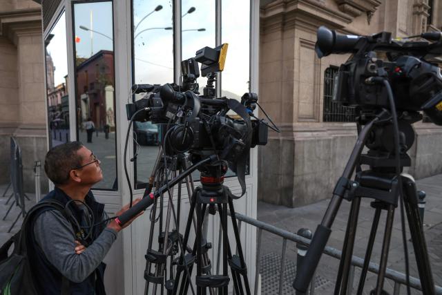 A camera man works outside the Government Palace in Lima on April 22, 2026. Peru's foreign and defense ministers resigned on April 22 in protest over the interim president's decision to stall a $3.5 billion deal for the purchase of 24 US F-16 fighter jets. (Photo by Connie FRANCE / AFP)