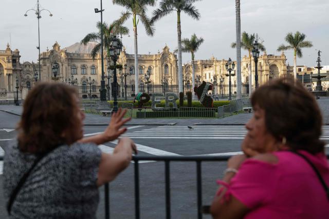 Women chat at Plaza Mayor with the Government Palace on the background in Lima on April 22, 2026. Peru's foreign and defense ministers resigned on April 22 in protest over the interim president's decision to stall a $3.5 billion deal for the purchase of 24 US F-16 fighter jets. (Photo by Connie FRANCE / AFP)