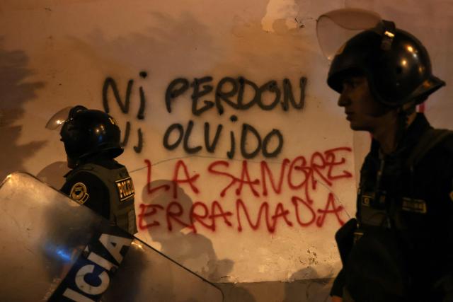 Riot police walk past graffiti reading “Neither forgiveness nor forgetting, the blood shed” during a protest over transport fares in Lima on April 22, 2026. (Photo by Connie FRANCE / AFP)