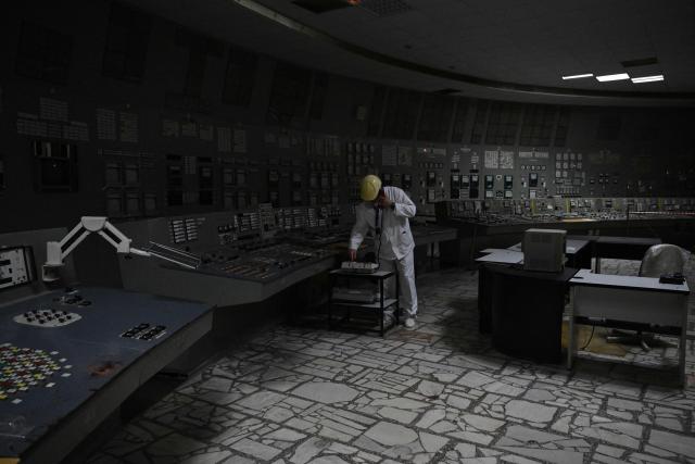 (FILES) Chornobyl Nuclear Power Plant deputy technical director for radioactive waste management Oleksandr Skomarokhov, uses a phone in the control room of the no longer working reactor 3 of the Chornobyl Nuclear Power Plant on April 9, 2026, amid the Russian invasion of Ukraine. Ukraine will on April 30, 2026 mark the 40th anniversary of the Chernobyl accident, the worst civilian nuclear disaster in history. The risks of new radioactive releases still remain today, as the site is threatened by Russian strikes after it invaded the neighbour four years ago. (Photo by Genya SAVILOV / AFP)