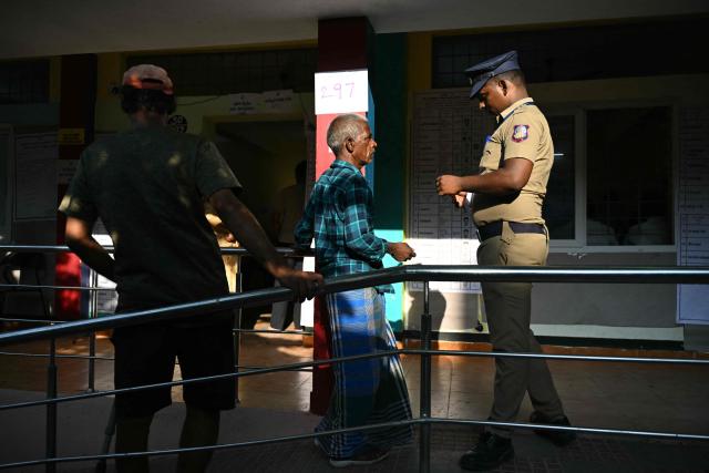 A voter has his papers checked before casting his vote outside a polling station during the 2026 Tamil Nadu Legislative Assembly elections in Chennai on April 23, 2026. (Photo by R.Satish BABU / AFP)
