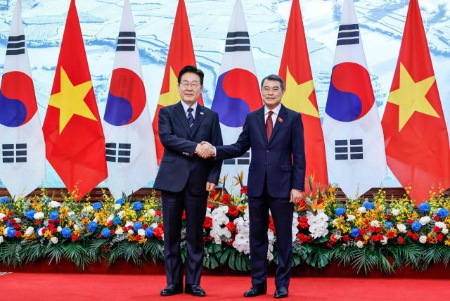 Vietnam's Prime Minister Le Minh Hung (R) and South Korea's President Lee Jae Myung (L) shake hands during a meeting at the Government Office in Hanoi on April 23, 2026. (Photo by LUONG THAI LINH / POOL / AFP)