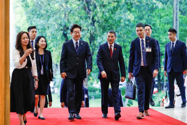 Vietnam's Prime Minister Le Minh Hung (C-R) and South Korea's President Lee Jae Myung (C-L) walk during a meeting at the Government Office in Hanoi on April 23, 2026. (Photo by LUONG THAI LINH / POOL / AFP)