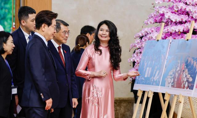 Vietnam's Prime Minister Le Minh Hung (4th L) and South Korea's President Lee Jae Myung (3rd L) look at photos displayed during a meeting at the Government Office in Hanoi on April 23, 2026. (Photo by LUONG THAI LINH / POOL / AFP)