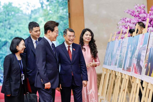 Vietnam's Prime Minister Le Minh Hung (C) and South Korea's President Lee Jae Myung (C-L) look at photos displayed during a meeting at the Government Office in Hanoi on April 23, 2026. (Photo by LUONG THAI LINH / POOL / AFP)
