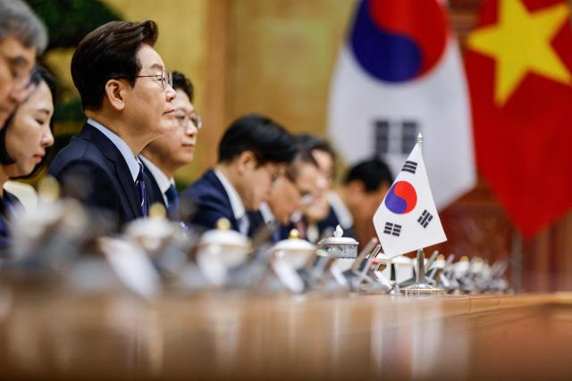 South Korea's President Lee Jae Myung (L) sits during a meeting with Vietnam's Prime Minister Le Minh Hung at the Government Office in Hanoi on April 23, 2026. (Photo by LUONG THAI LINH / POOL / AFP)