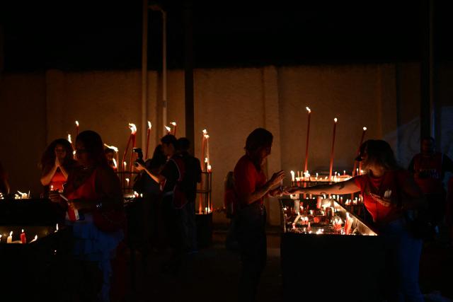People light candles during Saint George's Day (Sao Jorge) celebrations at the Quintino neighborhood in Rio de Janeiro, Brazil on April 22, 2026. (Photo by Pablo PORCIUNCULA / AFP)