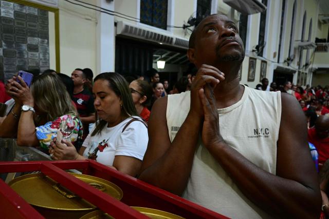 People pray during Saint George's Day (Sao Jorge) celebrations at the Quintino neighborhood in Rio de Janeiro, Brazil on April 22, 2026. (Photo by Pablo PORCIUNCULA / AFP)