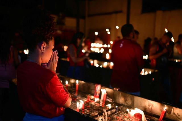 People pray during Saint George's Day (Sao Jorge) celebrations at the Quintino neighborhood in Rio de Janeiro, Brazil on April 22, 2026. (Photo by Pablo PORCIUNCULA / AFP)