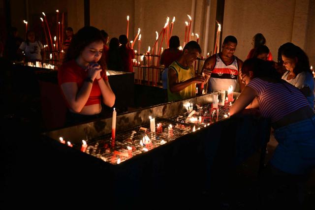 People pray during Saint George's Day (Sao Jorge) celebrations at the Quintino neighborhood in Rio de Janeiro, Brazil on April 22, 2026. (Photo by Pablo PORCIUNCULA / AFP)
