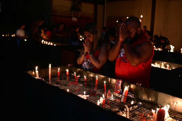 People pray during Saint George's Day (Sao Jorge) celebrations at the Quintino neighborhood in Rio de Janeiro, Brazil on April 22, 2026. (Photo by Pablo PORCIUNCULA / AFP)