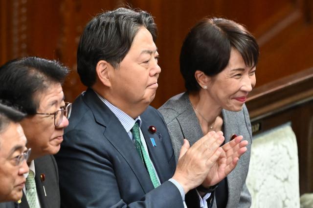 Japan's Prime Minister Sanae Takaichi (R) and her cabinet ministers react after the government's bill to establish a National Intelligence Council was passed by a majority vote of both ruling and opposition parties during a plenary session of the House of Representatives in Tokyo on April 23, 2026. (Photo by Kazuhiro NOGI / AFP)