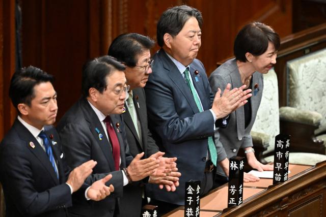 Japan's Prime Minister Sanae Takaichi (R) and her cabinet ministers react after the government's bill to establish a National Intelligence Council was passed by a majority vote of both ruling and opposition parties during a plenary session of the House of Representatives in Tokyo on April 23, 2026. (Photo by Kazuhiro NOGI / AFP)