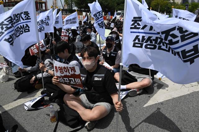 Members of the Samsung Electronics labour union hold flags as they stage a mass rally demanding the removal of a cap on performance bonuses, outside the company's foundry and semiconductor factory in Pyeongtaek on April 23, 2026. (Photo by Jung Yeon-je / AFP)