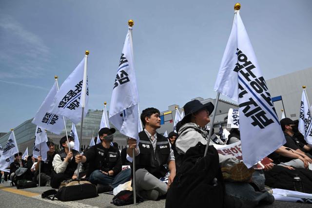 Members of the Samsung Electronics labour union hold flags as they stage a mass rally demanding the removal of a cap on performance bonuses, outside the company's foundry and semiconductor factory in Pyeongtaek on April 23, 2026. (Photo by Jung Yeon-je / AFP)