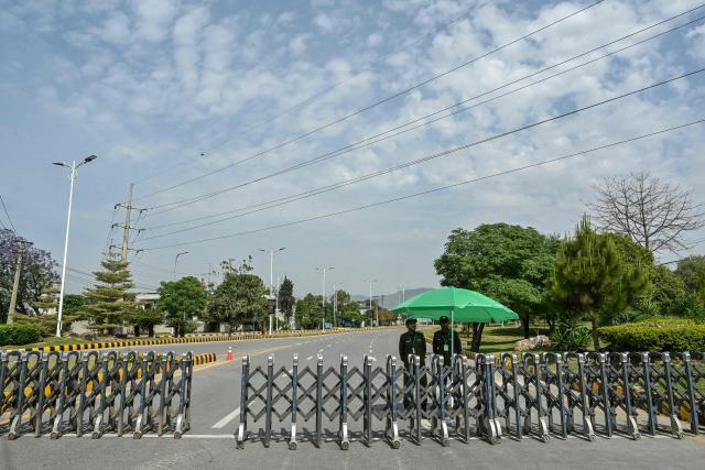 Security personnel stand guard at a closed road leading to the Serena Hotel in the Red Zone area of Islamabad on April 23, 2026. Pakistan's capital was still locked in gear on April 22 to host high-stakes US-Iran talks that were pushed back at the last minute overnight, but many residents began to tire of the heavy personal and economic toll of tight security restrictions. (Photo by Asif HASSAN / AFP)