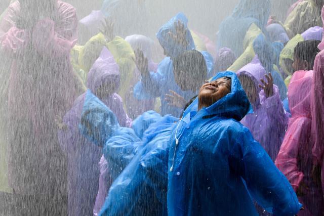 Kindergarten students react as they are sprayed with water while learning to use hoses with firefighters in Banda Aceh on April 23, 2026. (Photo by CHAIDEER MAHYUDDIN / AFP)