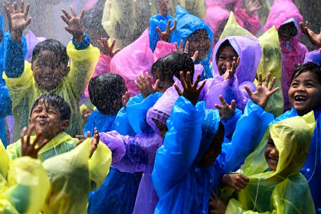 Kindergarten students react as they are sprayed with water while learning to use hoses with firefighters in Banda Aceh on April 23, 2026. (Photo by CHAIDEER MAHYUDDIN / AFP)
