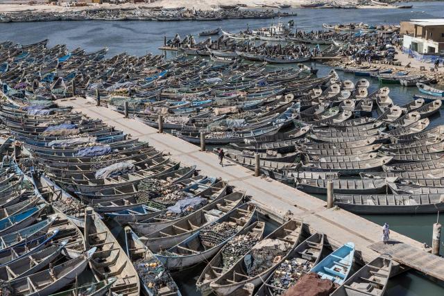 A fisherman walks past docked pirogues at the Port Artisanal in Nouadhibou, on April 22, 2026. (Photo by PATRICK MEINHARDT / AFP)