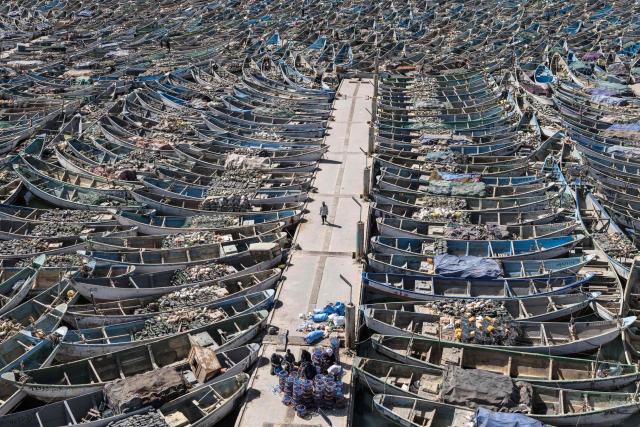 A fisherman walks past docked pirogues at the Port Artisanal in Nouadhibou, on April 22, 2026. (Photo by PATRICK MEINHARDT / AFP)