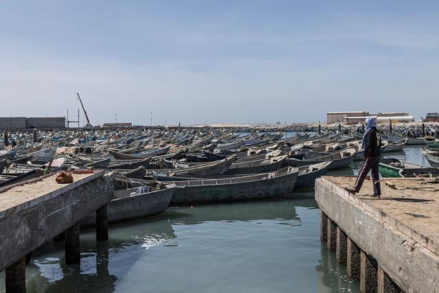 A fisherman looks at docked pirogues at the Port Artisanal in Nouadhibou, on April 22, 2026. (Photo by PATRICK MEINHARDT / AFP)