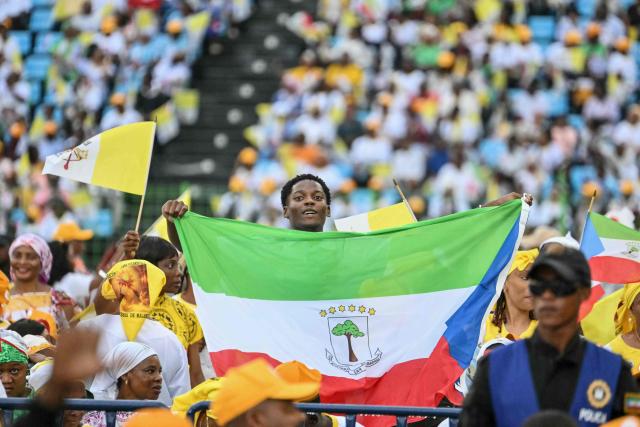 A faithful holds an Equatorial Guinea flag before Pope Leo XIV arrives to lead a Holy Mass at the Malabo Stadium in Malabo on the last day of an 11-day apostolic journey to Africa, on April 23, 2026. (Photo by Alberto PIZZOLI / AFP)