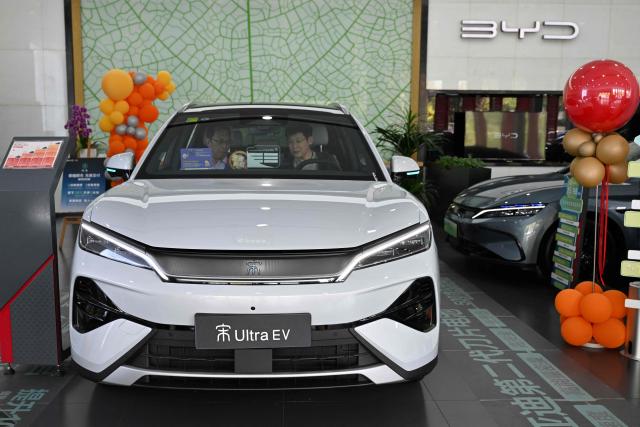 Customers examine an Ultra EV car at a BYD showroom in Beijing on April 23, 2026. (Photo by Adek BERRY / AFP)
