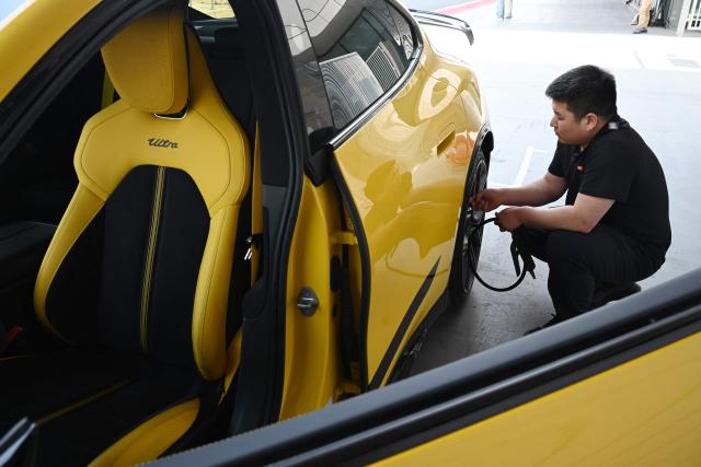 A technician checks tyre pressure on a Xiaomi SU7 Ultra during a Xiaomi track day driving experience in Tianjin, in northern China on April 23, 2026, ahead of the Beijing Auto Show which opens on April 24. (Photo by GREG BAKER / AFP)