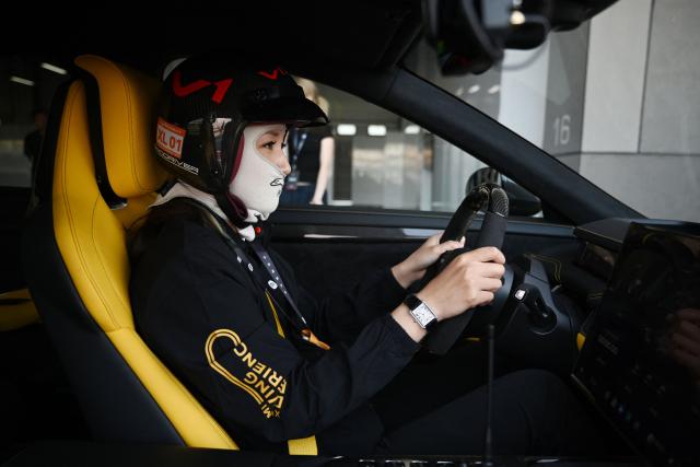 An instructor prepares to drive a Xiaomi SU7 Ultra on track during a Xiaomi track day driving experience in Tianjin, in northern China on April 23, 2026, ahead of the Beijing Auto Show which opens on April 24. (Photo by GREG BAKER / AFP)