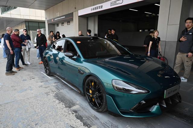 Journalists look at a Xiaomi SU7 Ultra in the pit lane during a Xiaomi track day driving experience in Tianjin, in northern China on April 23, 2026, ahead of the Beijing Auto Show which opens on April 24. (Photo by GREG BAKER / AFP)
