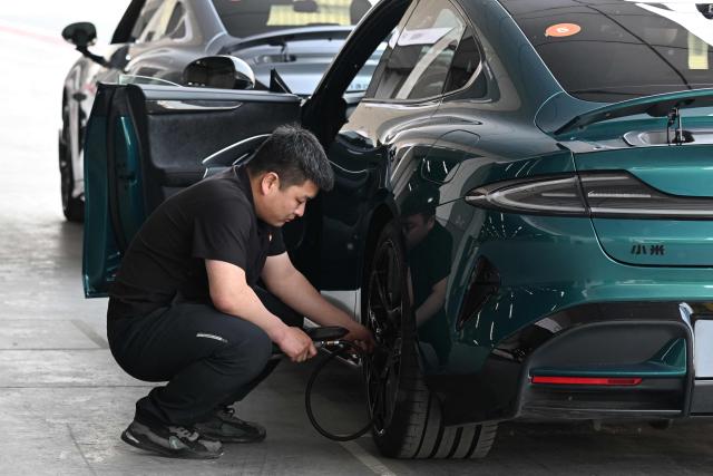 A technician checks tyre pressure on a Xiaomi SU7 Ultra during a Xiaomi track day driving experience in Tianjin, in northern China on April 23, 2026, ahead of the Beijing Auto Show which opens on April 24. (Photo by GREG BAKER / AFP)