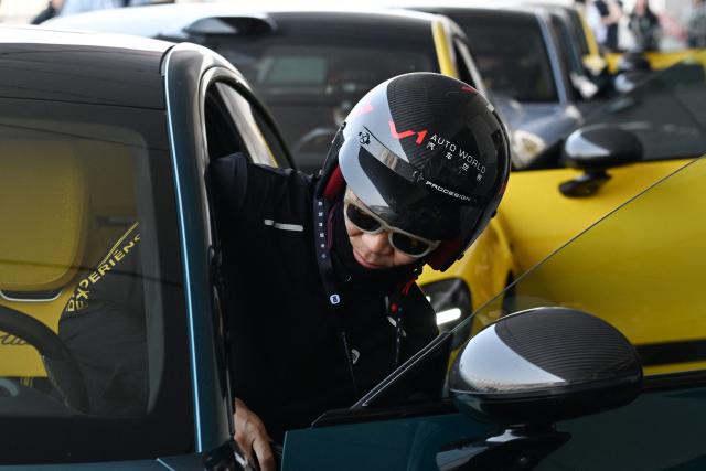 An instructor gets into a Xiaomi SU7 Ultra during a Xiaomi track day driving experience in Tianjin, in northern China on April 23, 2026, ahead of the Beijing Auto Show which opens on April 24. (Photo by GREG BAKER / AFP)