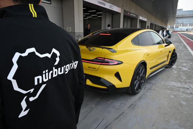 A Xiaomi staff member wearing a jacket with a map of the Nurburgring racing circuit stands next to a Xiaomi SU7 Ultra during a Xiaomi track day driving experience in Tianjin, in northern China on April 23, 2026, ahead of the Beijing Auto Show which opens on April 24. (Photo by GREG BAKER / AFP)